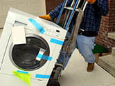 A professional labor worker moves a washing machine out of a home on at heavy duty dolly with wheels