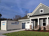 A 1-800-PACK-RAT portable storage container sits in a home's driveway