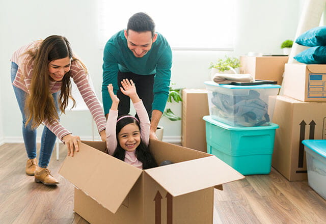 A young couple pushes their happy daughter in a box