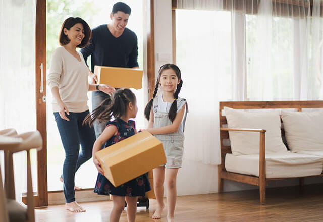 A family carries boxes in their home