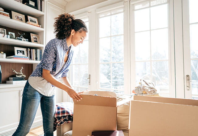 A woman packs boxes in her home