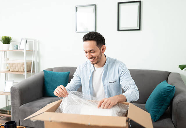 A man packs items in a box with bubble wrap