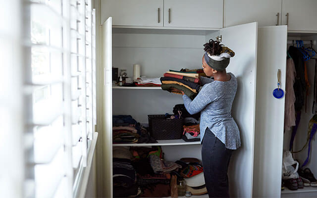 A woman puts away folded clothes into a closet