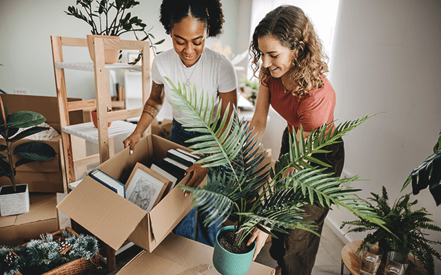 Two women unpack boxes in their new home