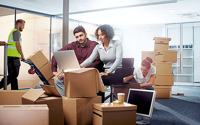 A group of employees and a labor provider pack and move boxes out of their office area