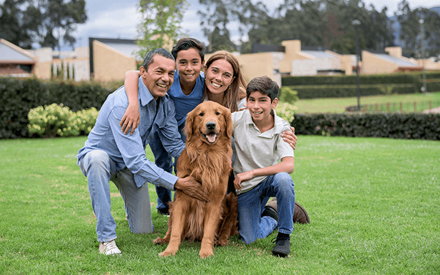 A happy family with two kids and a dog pose for a picture in their backyard