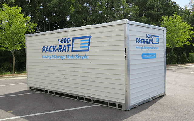 A 1-800-PACK-RAT 16-foot portable storage container sits in an empty parking on a bright sunny day with its side and back facing the viewer