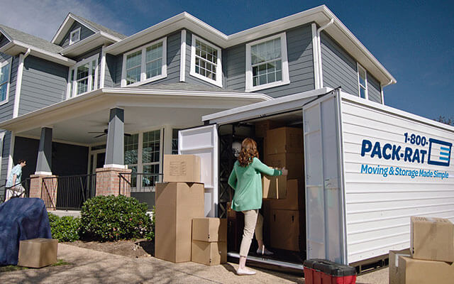 A woman packs her 1-800-PACK-RAT portable storage container with boxes as she and her family move out of their suburban home