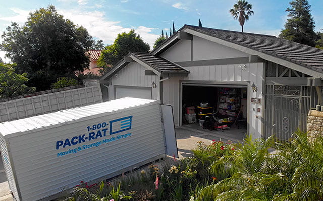 A 1-800-PACK-RAT portable storage container sits in a home's driveway open as homeowners put belongings inside it