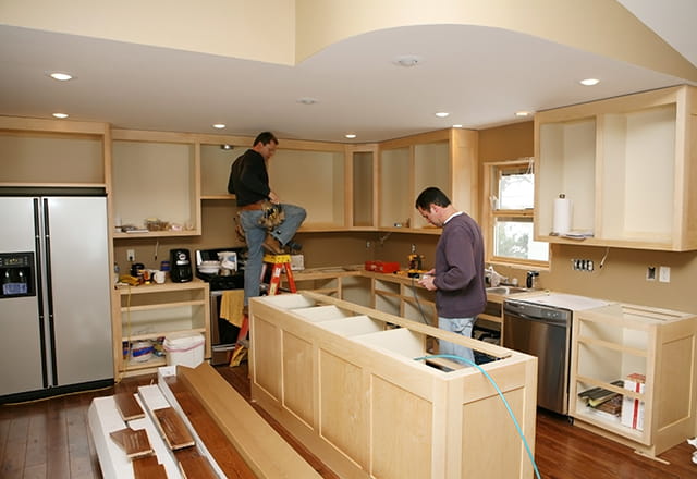 Two men work on renovation a home kitchen