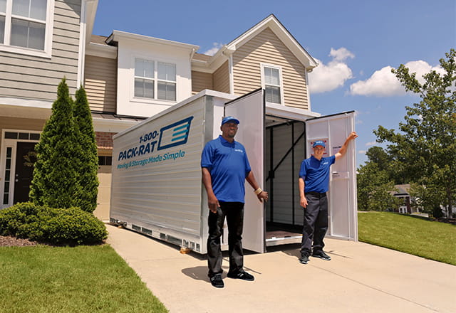 Workers stand in front of an open 1-800-PACK-RAT portable storage container