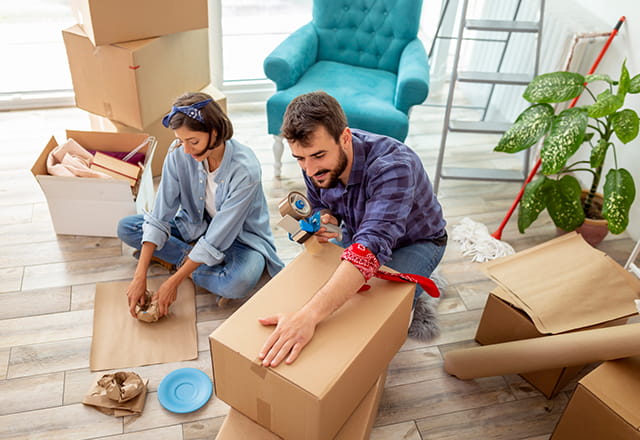 A younger couple packs boxes in their home