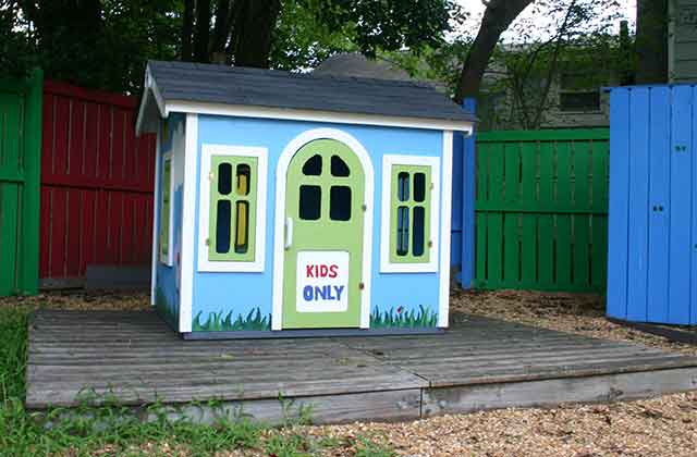 The children's playhouse 1-800-PACK-RAT made with Habitat for Humanity sitting in a garden at Passage Home.