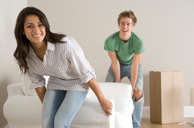 Friends help each other move a couch.