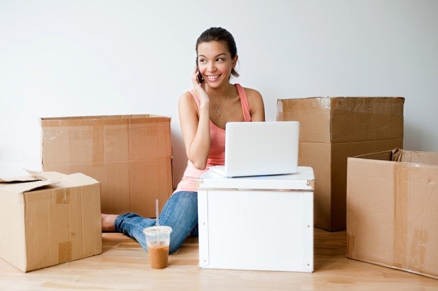 Woman surrounded by moving boxes makes checklist.