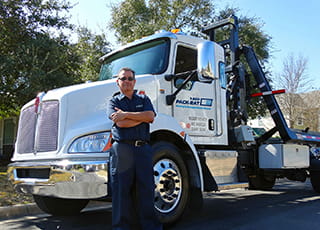 A confident 1-800-PACK-RAT driver stands in front of his truck