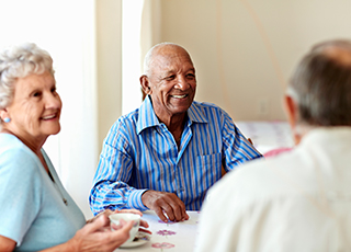 A group of elderly people enjoy each other's company and a card game