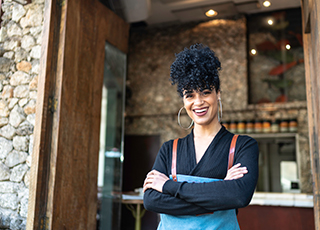 A confidant looking woman stands in the doorway of her restaurant