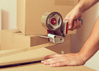 A person tapes a box shut with a tape gun