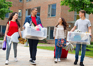 A group of students carry their belongings out from the dorms