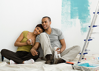 Happy couple rests while they are painting a room in their home