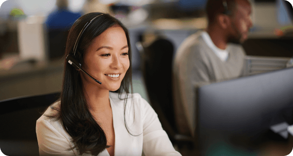 A customer service representative smiles as she assists a customer on the phone