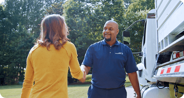 A 1-800-PACK-RAT driver shakes hands with a customer as he drops off her container at her home