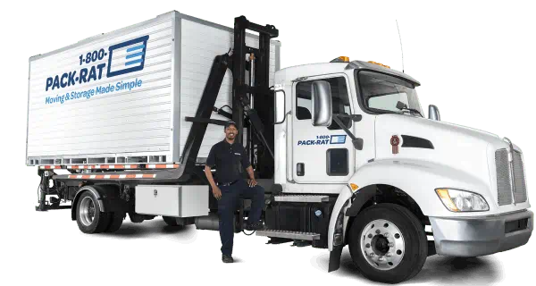 A 1-800-PACK-RAT driver stands next to his mini-mover truck with a portable storage container sitting on the back of it