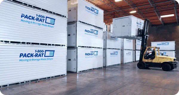 A large number of 1-800-PACK-RAT portable storage containers sit in a warehouse as one is put away by a forklift