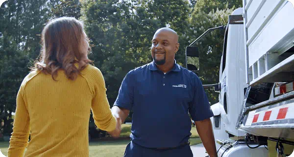 A 1-800-PACK-RAT truck driver greets and shakes hands with a customer has he is delivering her container to her home