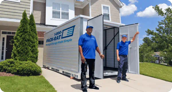 Two 1-800-PACK-RAT employees stand in front of an open 1-800-PACK-RAT portable storage container in a home's driveway