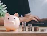 A piggy bank sits on a desk next to stacks of coins