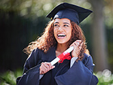 A college graduate smiles while holding her rolled up diploma