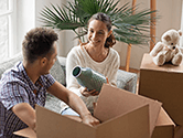 A man and woman pack a vase into a box with other fragile items