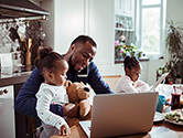 A father sits with his two daughters in their home while on the phone