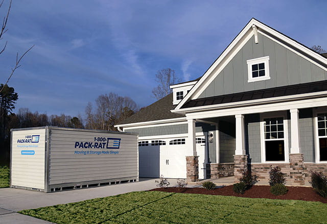 A 1-800-PACK-RAT portable storage container sits in a home's driveway