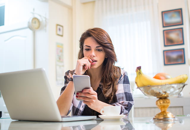 A woman anxiously reads on her phone