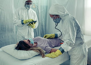 Two medical professionals tend to a patient while in protective gear