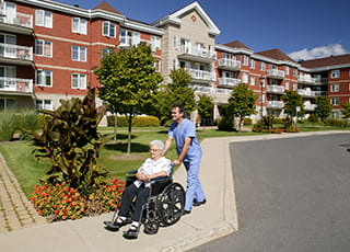 A nurse pushes a nursing home resident in her wheelchair