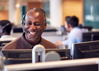 A smiling customer service rep assists a customer on the phone