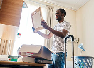 A college student examines his stuff in his room