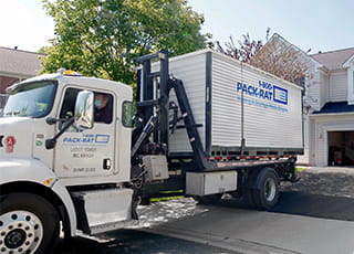 A 1-800-PACK-RAT mini-mover drops off a portable storage container at a home