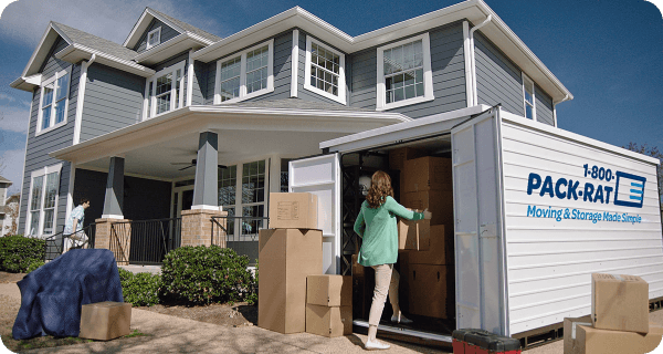 A customer load boxes into her 1-800-PACK-RAT portable storage container in her home's driveway on a sunny day