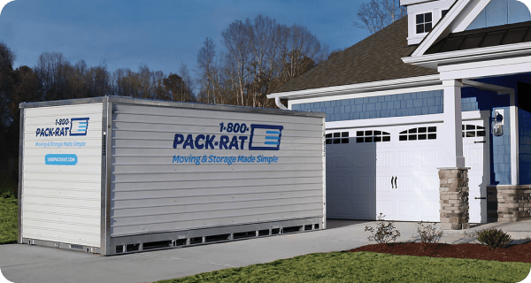 A 1-800-PACK-RAT portable storage container sits in front of the suburban home in its driveway