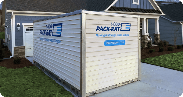 A 1-800-PACK-RAT portable storage container sits in the driveway of a home