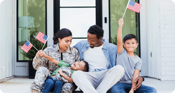 A military family sits on their front porch having fun and waving American flags