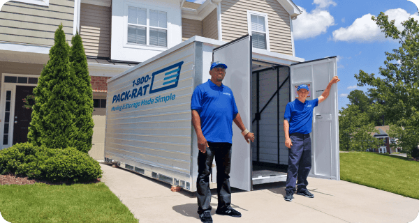 Two 1-800-PACK-RAT employees stand in front of an open 1-800-PACK-RAT portable storage container in a home's driveway