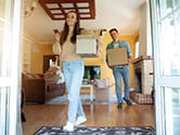 A young couple carries boxes into their new home as they begin to stage their belongings