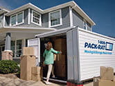 A woman packs her 1-800-PACK-RAT portable storage container with boxes as she and her family move out of their suburban home