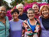 A group of multiracial older adults and friends pose and smile for a photo on a sunny morning